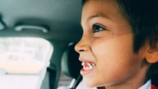 A close-up of a child's side profile who's showing his teeth