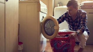 A husband taking laundry out of a machine because he and his wife believe teamwork makes the dream w...