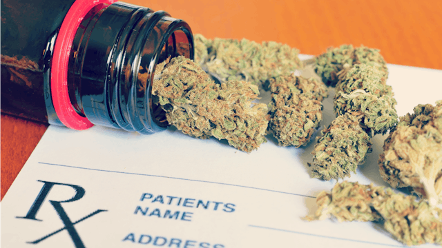 Marijuana falling out of a medication bottle on a prescription paper.