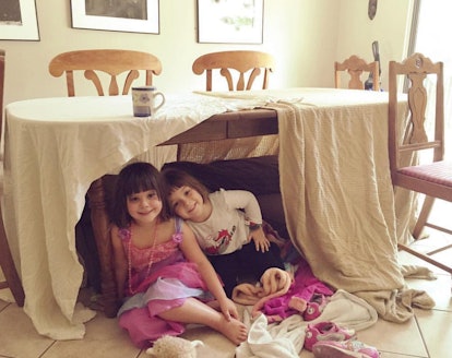 Two girls in a hideout with pillows under a table