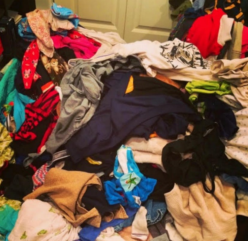A large messy pile of clothes in a bedroom placed next to a white door