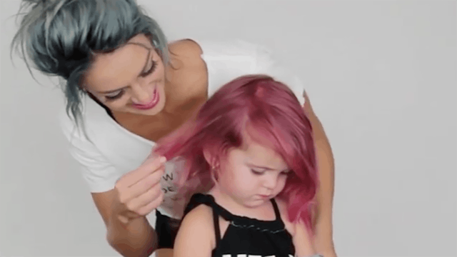 A mother who dyed her hair light blue/gray, touching a hot pink hair of her 2-year-old daughter.
