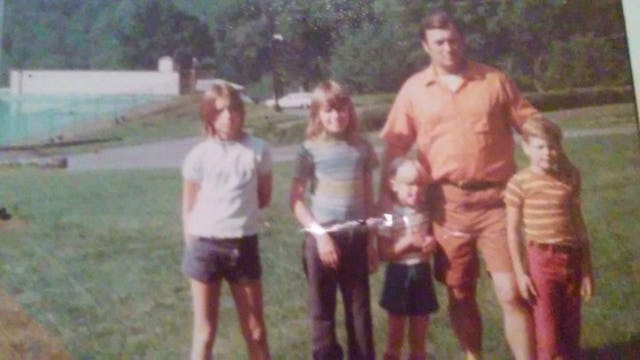 A father posing for a photo with his two sons and two daughters