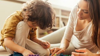 A divorced mom playing on the floor with her son, with Legos.