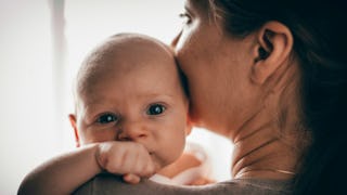 A woman going through the fourth trimester holding her newborn baby close to her face