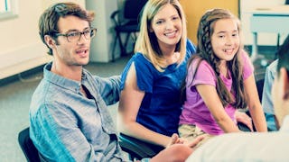 A girl sitting in her mother's lap, with her father sitting next to them at an IEP meeting