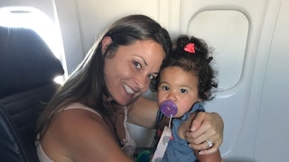A mother posing with her toddler girl in an airplane