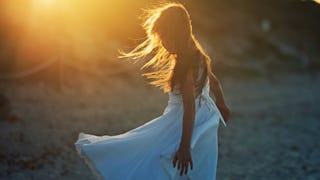 A non-binary child taking a photo in a white dress