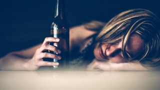 A sad and drunk woman that has alcoholism issues holds a beer