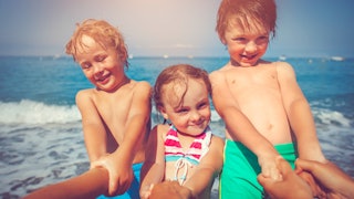 Two Little Boys And A Little Girl Posing On A Beach 