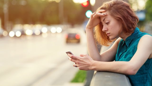 An unemployed mom looking irritated, facing down looking at her cell phone