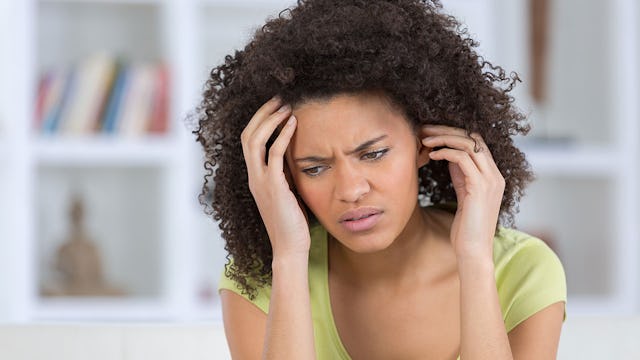 A woman with symptoms of panic and anxiety disorders holding her head with a worried expression on h...