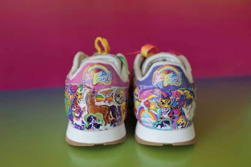 The backside of a pair of really colorful Lisa Frank Reebok Sneakers standing on yellow and pink bac...