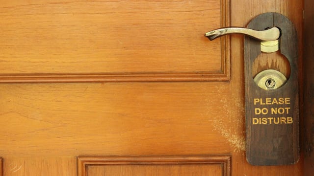 A do-not-disturb sign hooked on a doorknob of a teenage son's room.