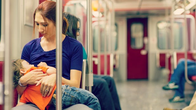 A young brown-haired mother breastfeeding her child in the train 