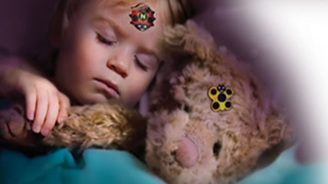 A child sleeping with a toy and a fever sticker on both of their heads checking the temperature