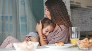 A stepmom holding her stepdaughter to her chest comforting her over breakfast