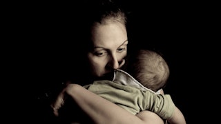 Dark place in which a woman is holding her baby, looking worried