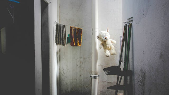 A white teddy bear hanging on drying rope with two pieces of cloth and cleaning tools