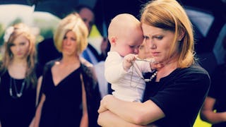 A mother holding and hugging her baby at a funeral