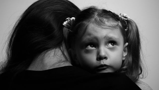 Mother with PTSD hugging a sad girl with pigtails.