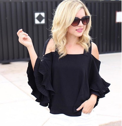 A blonde woman in a black 'Cold-Shoulder' black blouse and black sunglasses