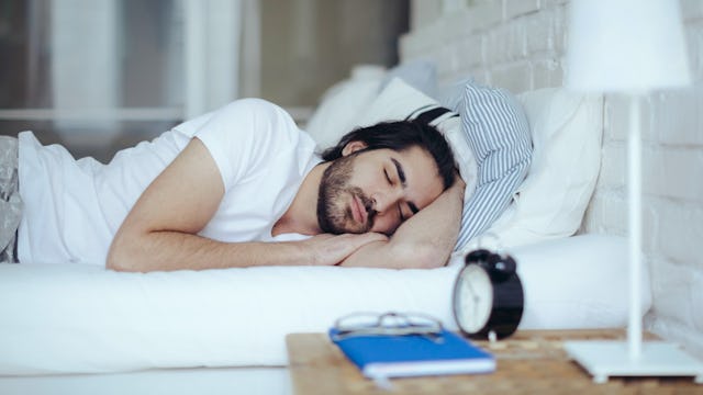 A man in a white shirt sleeping in a bed in a separate bedroom away from his wife