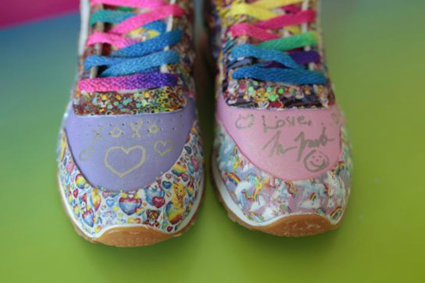 The front side of a pair of really colorful Lisa Frank Reebok Sneakers standing on yellow and pink b...