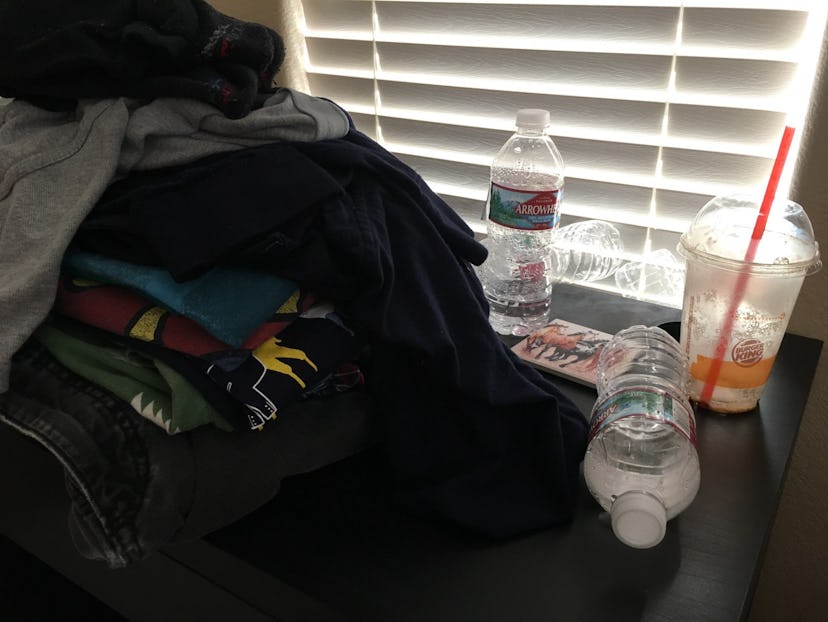 A table fully covered with clothes and empty water and juice bottles.