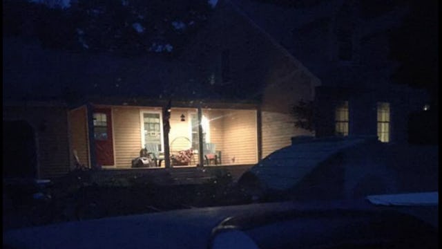 The entrance deck of a house with the porch light on during night time