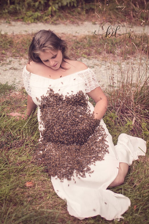 A pregnant woman in a white wedding dress is holding her belly with one arm while a swarm of bees is...