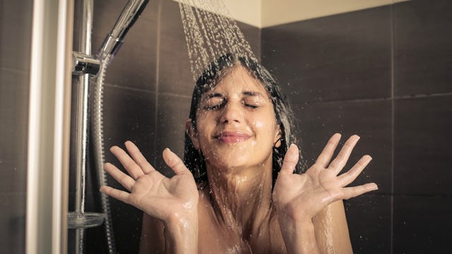A mom taking a shower with water running down her hair and face