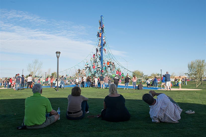 Parents sitting on the grass and watching their children playing at Riverview Park in Mesa, Arizona.