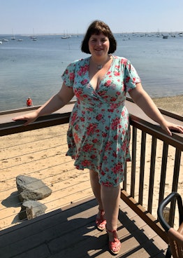 Erin Morrison-Fortunato wearing a blue floral-patterned dress while standing on a deck at a beach