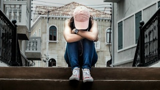 A person who has struggled with Trichotillomania sitting on steps with her head down