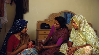 Two women helping a new mom in India during her postpartum period.