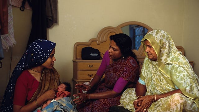 Two women helping a new mom in India during her postpartum period.