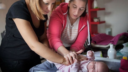A nurse making a routine house call to help a mother in a postpartum state in France.