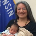 Lawmaker who was banned from public breastfeeding holding a newborn baby in front of the Wisconsin f...