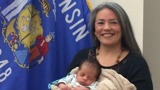Lawmaker who was banned from public breastfeeding holding a newborn baby in front of the Wisconsin f...