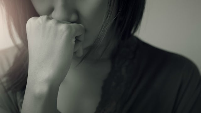 Sad and emotionally abused woman leaning her hand on her cheek in black and white