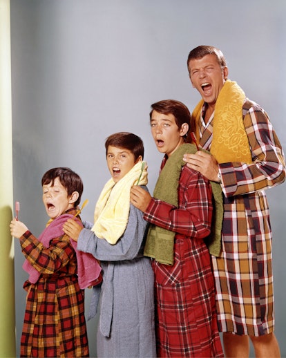 The Brady Bunch father and his three sons standing in robes with towels around their necks with thei...