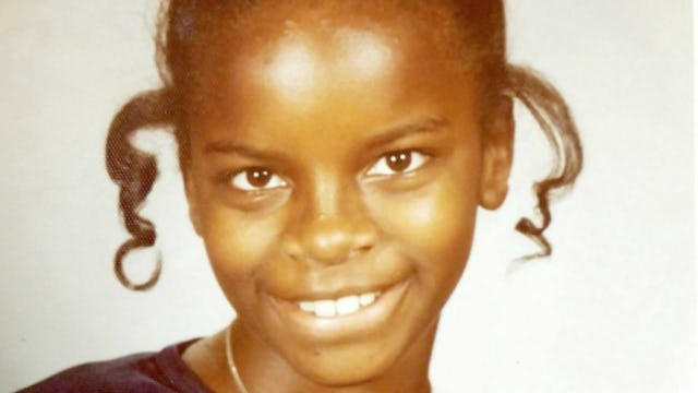 A portrait of a teenage girl smiling in a black top