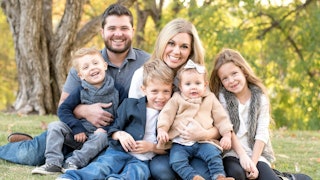 Parents posing with their 4 kids for the family picture in the nature 