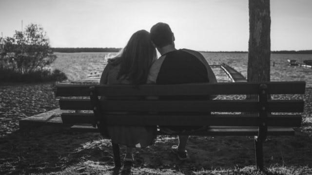 A woman who regrets keeping her miscarriage a secret and a man leaning onto each other on a bench