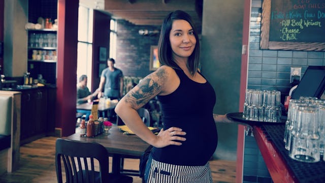 A pregnant waitress in the restaurant in a black top