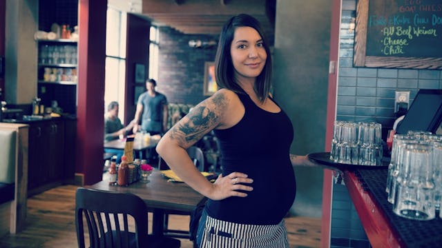  A pregnant waitress in the restaurant in a black top