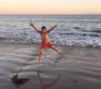 A boy in red shorts jumping and having fun at a beach