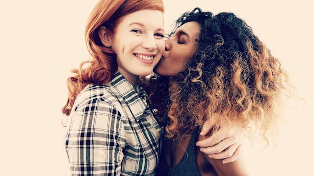 Two girl best friends hugging each other and kissing on the cheek