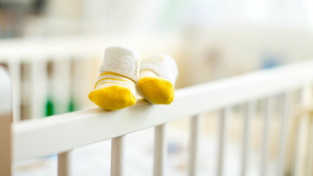 Yellow-and-white baby shoes placed on the fence of the baby's crib 